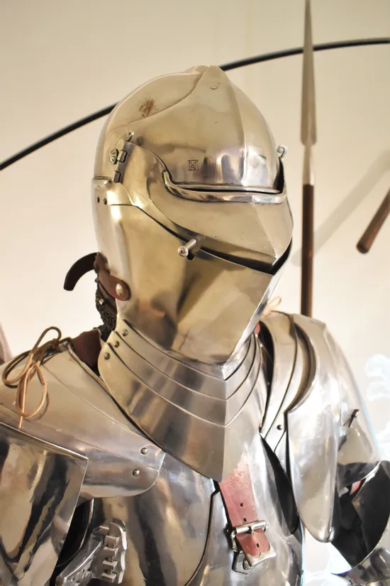 Mittelalterliche Ritterrüstung mit geschlossenem Helm und polierter Metalloberfläche ausgestellt